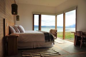 Schlafzimmer mit einem Bett und Blick auf das Wasser in der Unterkunft Hotel Simple Patagonia in Puerto Natales