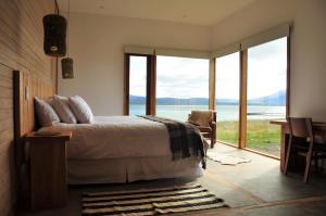 a bedroom with a bed and a view of the water at Hotel Simple Patagonia in Puerto Natales