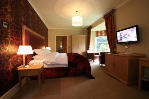 Habitación de hotel con cama y TV en Farington Lodge Hotel, en Preston