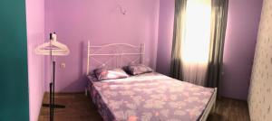 Dormitorio púrpura con cama y lámpara en SunSet en Pizunda