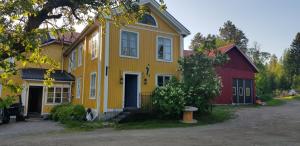 una casa amarilla y roja con un granero rojo en Nygården B&B Hälsingegård en Harmånger