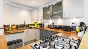 a kitchen with white cabinets and a stove top oven at COSY RIVERVIEW-LONDON EXCEL CENTRE-O2 ARENA in London