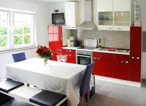 a kitchen with red cabinets and a white table with chairs at Zimmervermietung Roy in Cologne