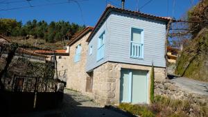 a stone house with white doors on a hill at Casa Sulfato in Campo do Gerês