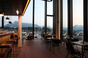restauracja ze stołami i krzesłami oraz dużymi oknami w obiekcie arte Hotel Salzburg w mieście Salzburg