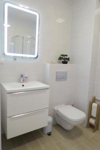 a white bathroom with a toilet and a mirror at Biały apartament in Kołobrzeg