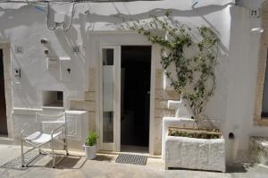 a white house with a chair and a plant at Latorreangioina in Ostuni