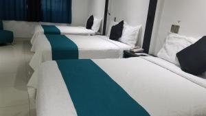 2 bedden in een hotelkamer met witte en blauwe lakens bij Hotel Dluxe in San Juan de los Lagos