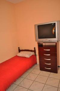 ein Schlafzimmer mit einem Bett und einem TV auf einer Kommode in der Unterkunft Hospedagem Centro Champagnat in Londrina