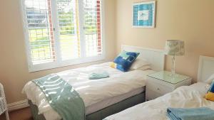 a bedroom with two beds and a lamp on a night stand at Keurbooms River Lodge 21 in Keurboomstrand