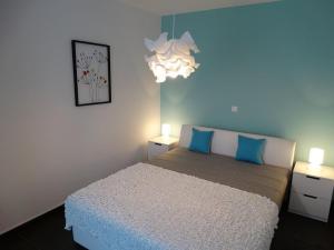Un dormitorio con una cama con almohadas azules y una lámpara de araña. en Apartment Adriana 2 (ground floor), en Mušalež