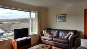 a living room with a couch and a large window at Skerryvore in Oban
