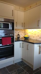 a kitchen with white cabinets and a microwave at Skerryvore in Oban