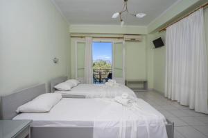 two beds in a room with a window at Ionian Melody in Nikiana