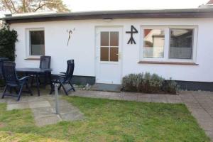 een tafel en stoelen voor een wit huis bij Ferienhaus in Plogshagenauf Hidden in Neuendorf