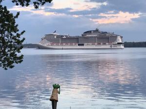 a cruise ship in the water with a woman standing on the shore at Kajüte Holtenau in Kiel