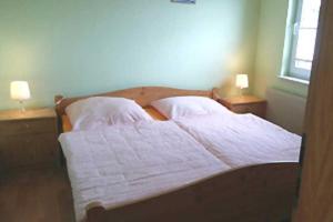um quarto com 2 camas com lençóis brancos e 2 candeeiros em Ferienhaus in Plogshagenauf Hidden em Neuendorf