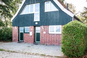 a red brick house with a black roof at Zugvogel OG in Wangerland