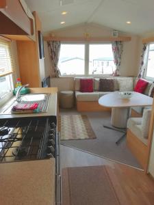 a kitchen and living room with a stove and a couch at Swanage Bay View caravan in Swanage