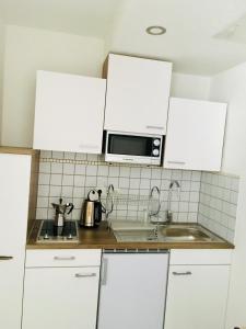 een keuken met witte kasten en een magnetron bij FeWo Marussia in Rust