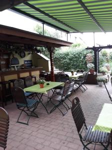 un patio avec des tables et des chaises sous un parasol vert dans l'établissement Zwehrener Hof, à Cassel