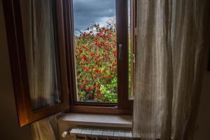 uma janela com vista para um arbusto de flores vermelhas em Alghero in bicicletta em Alghero