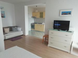 a living room with a tv on a dresser and a kitchen at Feel good apartment in Banjol