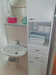 baño con lavabo y armario blanco con toallas en Feel good apartment en Banjol