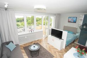 een woonkamer met een televisie en een bank bij Apartament Skwer 13 in Gdynia