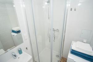 een witte badkamer met douche en wastafel bij Apartament Skwer 13 in Gdynia +14 foto's