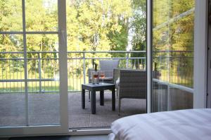 Schlafzimmer mit einem Bett und einem Tisch auf dem Balkon in der Unterkunft Hotel Müritz-Park in Boek