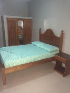 Schlafzimmer mit einem Holzbett und einem Spiegel in der Unterkunft Pensao Motel Sodade in São Filipe