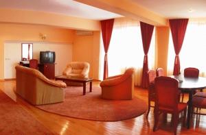 uma sala de estar com uma mesa e cadeiras e uma televisão em Hotel Maria em Râmnicu Vâlcea