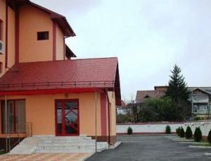 un edificio con techo rojo y aparcamiento en Hotel Maria en Râmnicu Vâlcea