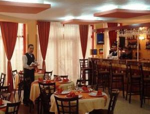 un hombre de pie en un restaurante con mesas y sillas en Hotel Maria en Râmnicu Vâlcea