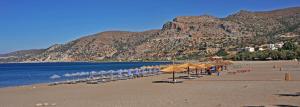a beach with umbrellas and chairs and the ocean at Villa Christina Anidri in Ánidhroi