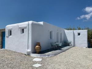 un edificio blanco con sillas y un jarrón al lado en Fortina Mykonos house, en Klouvas