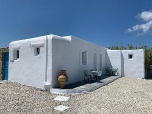 a white building with chairs and a vase next to it at Fortina Mykonos house in Klouvas