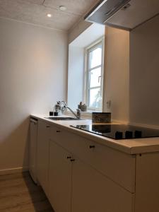 吉弗Hedegaard Holiday Apartments的带水槽和窗户的白色厨房