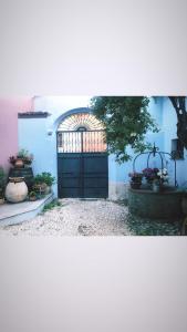 une porte noire dans un bâtiment bleu orné de fleurs dans l'établissement Vesta, à Sorgono