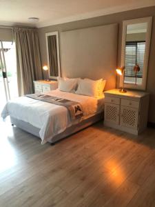 1 dormitorio con 1 cama con 2 mesitas de noche y espejo en Annies Place Self Catering, en Kempton Park