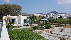 een wit huis met een tuin en gebouwen bij Amorgos Pearls in Katápola