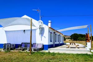 a white building with two chairs and a table at Monte Costa LuZ in Porto Covo