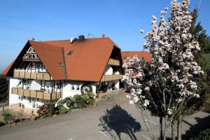 ein Haus mit einem roten Dach und einem Baum in der Unterkunft Wilderer Stube in Sasbachwalden