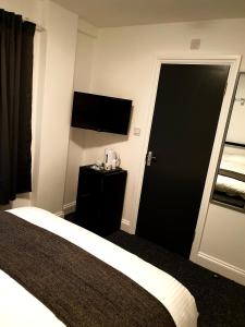 a bedroom with a television and a bed at Wanstead Hotel in London