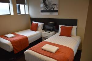 Habitación con 2 camas y sábanas de color naranja y blanco. en Apartments on Chapman, en Melbourne