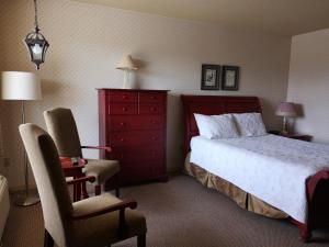 a bedroom with a bed and a chair and a dresser at Hotellerie Jardins de Ville in Sherbrooke +27 photos