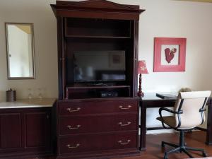 a dresser with a television and a desk with a chair at Hotellerie Jardins de Ville in Sherbrooke