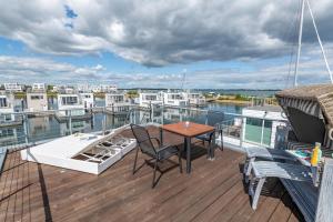 a deck with a table and chairs on a boat at Schwimmendes Haus Sea Breeze in Olpenitz