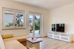 een woonkamer met een bank en een flatscreen-tv bij Apartments Valentina in Premantura